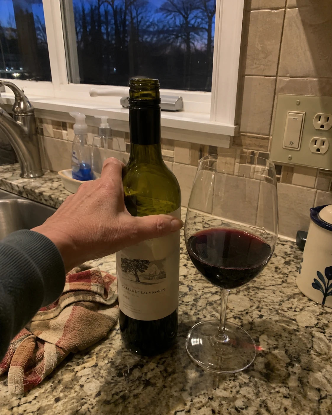 Wine bottle and glass on a kitchen counter at dusk