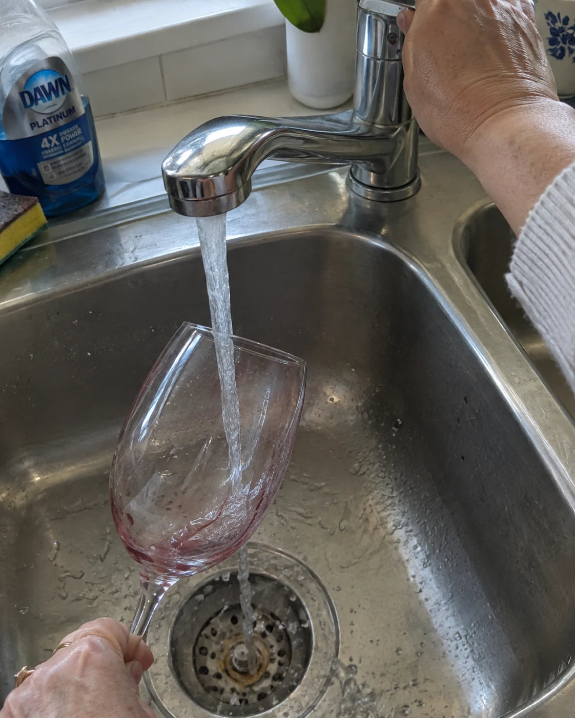 Rinsing an empty wine glass in the kitchen sink the next morning