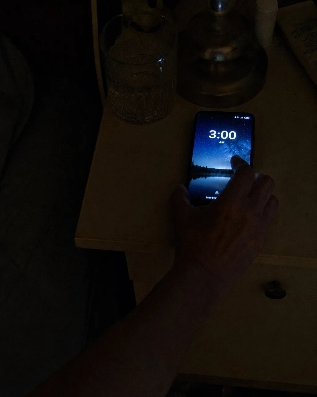 Phone glowing 3am on a dark nightstand
